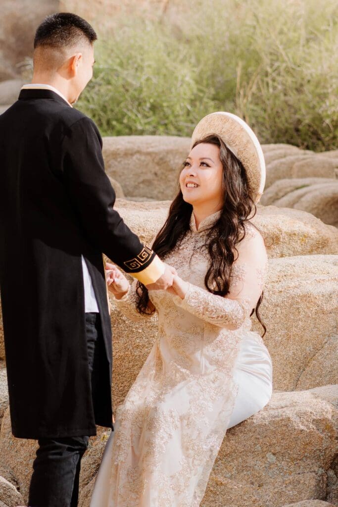 Vietnamese couple in traditional Ao Dai sharing a joyful moment during their Cap Rock elopement in Joshua Tree