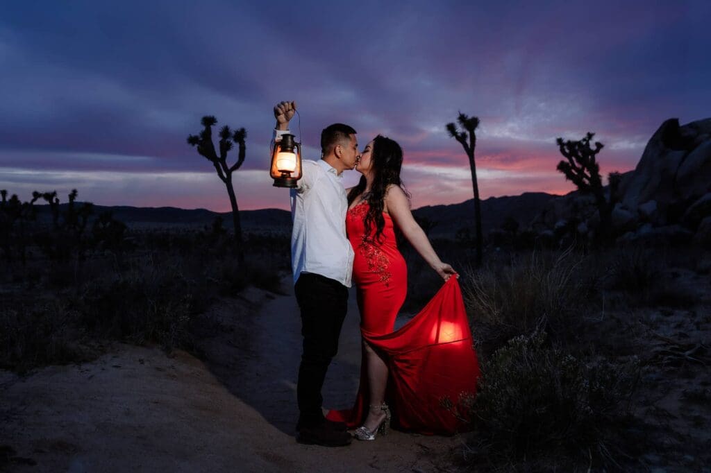 Couple kissing at Hidden Valley holding a lantern with a vibrant purple and pink sunset sky in the background