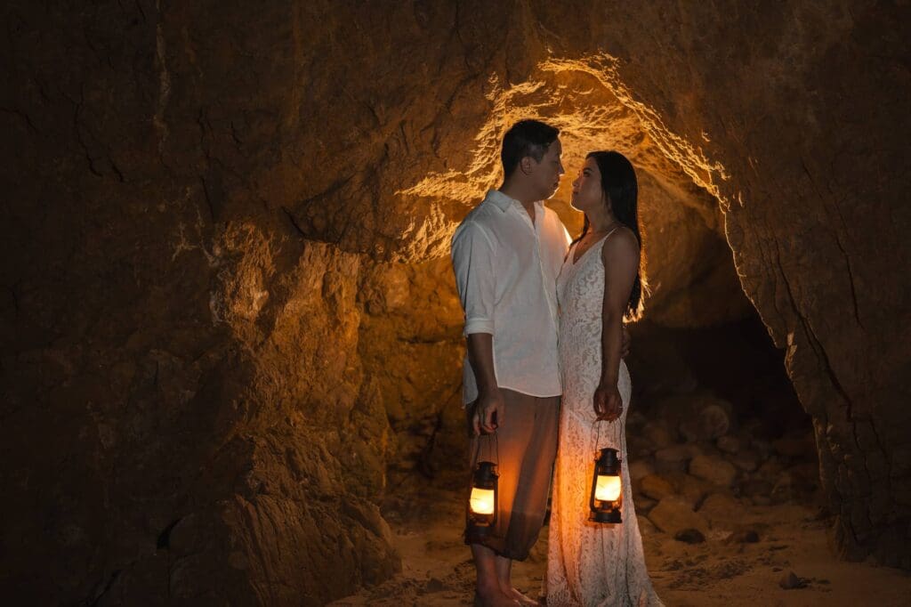Bride and groom holding lanterns inside a warm cave at El Matador State Beach during their Malibu elopement