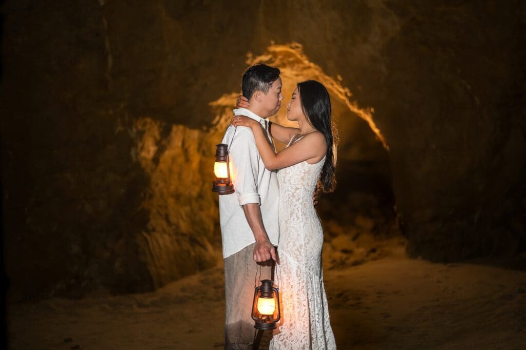 Couple holding lanterns during their Malibu elopement inside a glowing cave at El Matador Beach