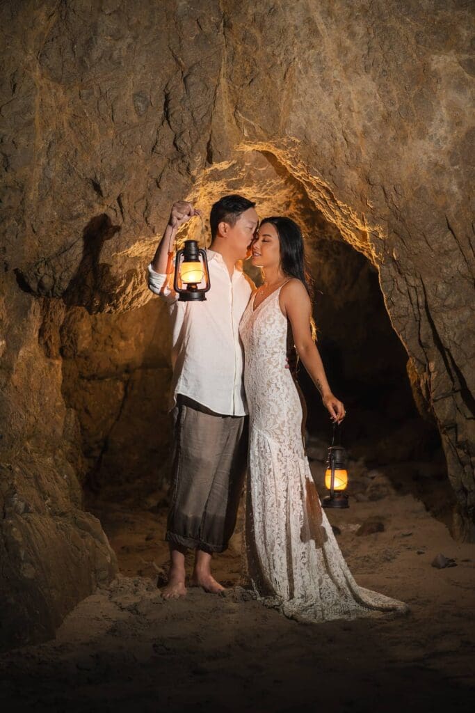 Groom lifting lantern and kissing bride inside a sea cave at El Matador State Beach in Malibu