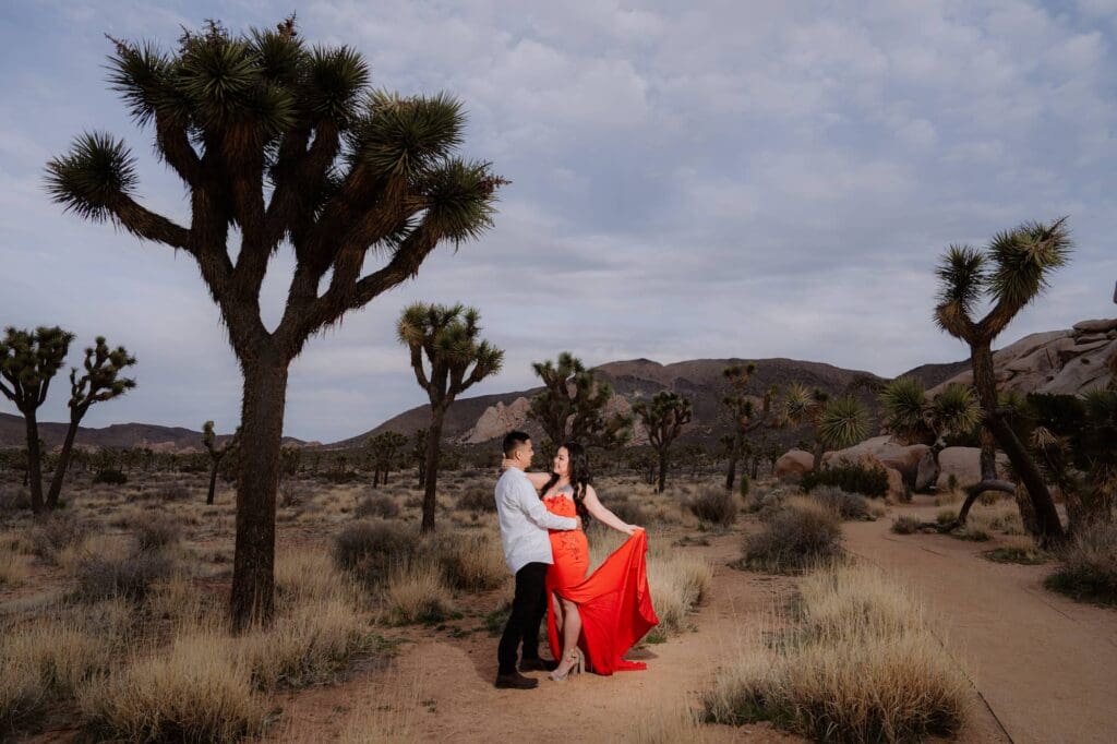 Bride in vibrant red Ao Dai dress posing with groom in Hidden Valley during their Vietnamese elopement in Joshua Tree