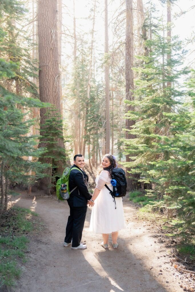 Couple hiking together on a forest trail before their Yosemite elopement at Taft Point