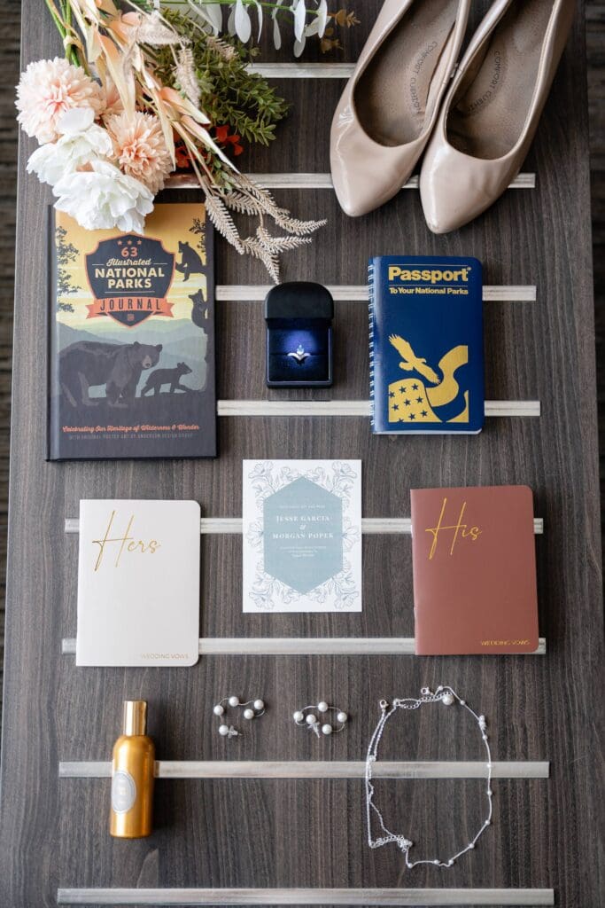 Wedding vow books, Yosemite passport, jewelry, and invitation for national park elopement Detail flat lay with vow books, wedding rings, and National Park gear
