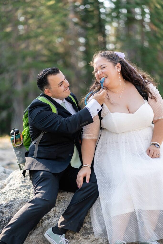 Groom playfully helping bride drink from hydration pack before their Yosemite elopement ceremony