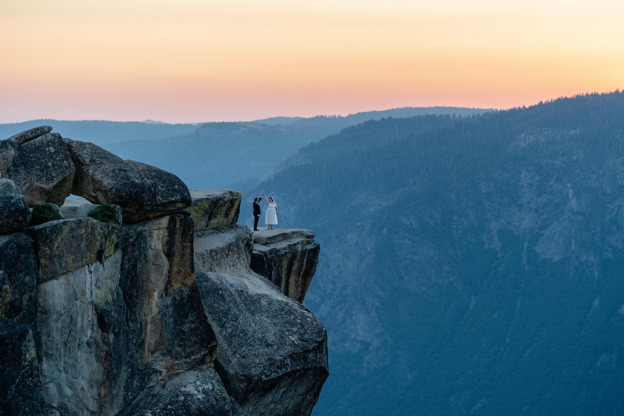 Couple standing on the cliffs of Taft Point during their Yosemite elopement at sunset