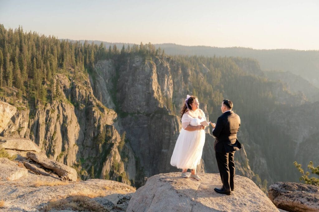 Yosemite elopement couple exchanging vows on the cliffs of Taft Point with golden hour light