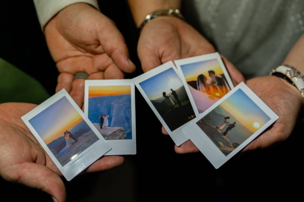 Hands holding Polaroids of Morgan and Jesse’s Yosemite elopement at sunset on Taft Point