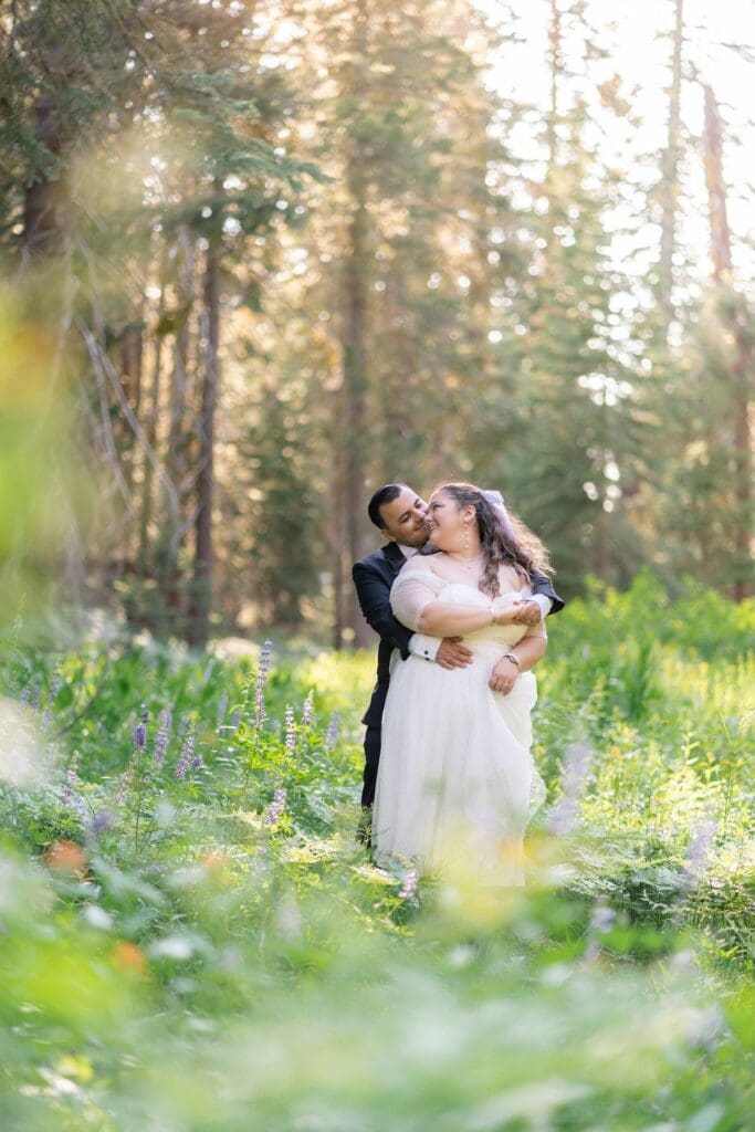 Groom hugging bride in a wildflower meadow during their elopement in Yosemite National Park